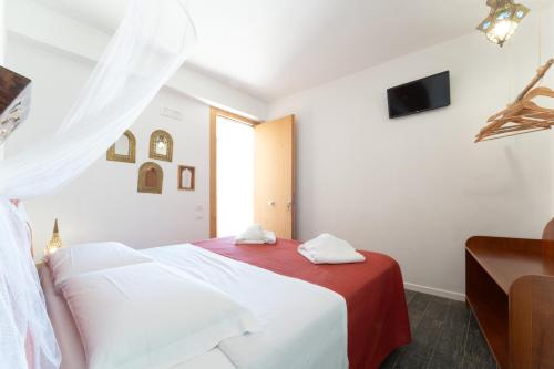 a white bedroom with a bed with a red blanket at Ajamola in Favignana