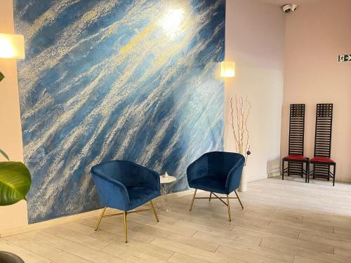 two chairs in a room with a large painting on the wall at Blue Shades Hotel in Pisa