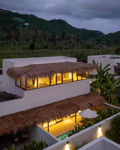 a view of a building with a thatch roof at Amber Lombok Beach Resort in Selong Belanak
