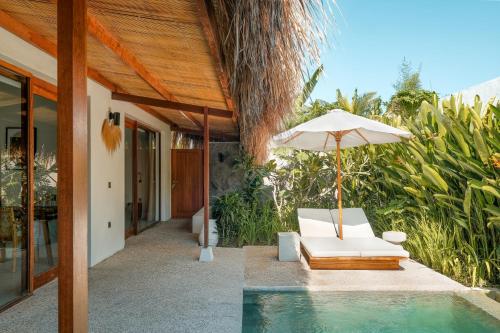 an umbrella and a chair next to a pool at Amber Lombok Beach Resort in Selong Belanak