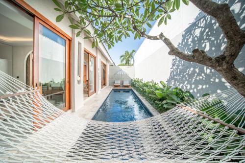 スミニャックにあるAstera Villa Seminyak by Ini Vie Hospitalityのスイミングプール付きの家の前のハンモック