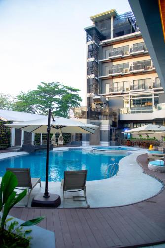 a swimming pool with chairs and umbrellas next to a building at Badsbrotel Suites in Ipil