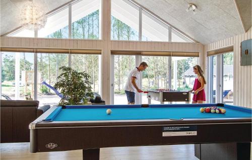 a man and woman standing in a room with a pool table at Holiday Home Nexø With Fireplace 04 in Snogebæk