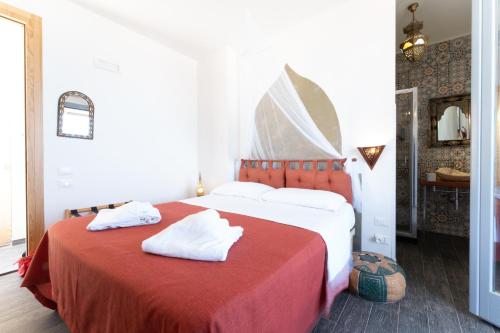 a bedroom with a red bed with white towels on it at Ajamola in Favignana