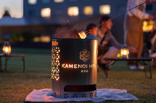 a container with a fire in it on the grass at KAMENOI HOTEL Aso in Aso