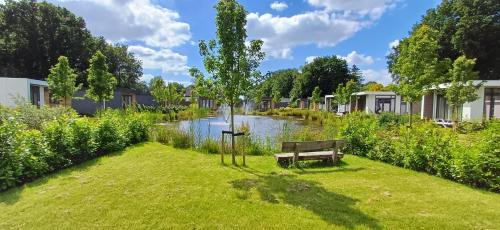 a park with a bench in the grass next to a river at TOP Luxe chalet - kindvriendelijk - bos en heide in Harderwijk