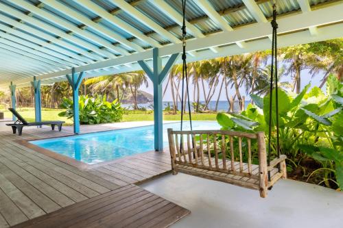 サント・マリーにあるMaison d'Ô Baie de Saint-Jacques, sur une plage sauvageのポーチ(ブランコ付)とスイミングプール