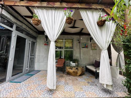 a patio with curtains and a couch on a house at Art House Sweet home in Shymkent