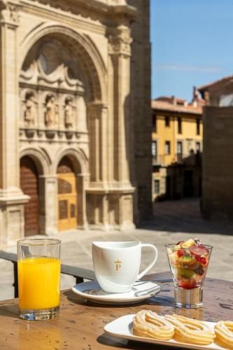 a table with a cup of orange juice and a cup of food at Parador de Santo Domingo de la Calzada in Santo Domingo de la Calzada