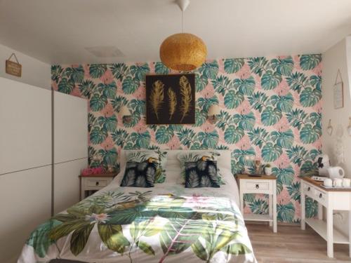 a bedroom with a bed with a tropical wallpaper at Les nids de la Baie in Favières
