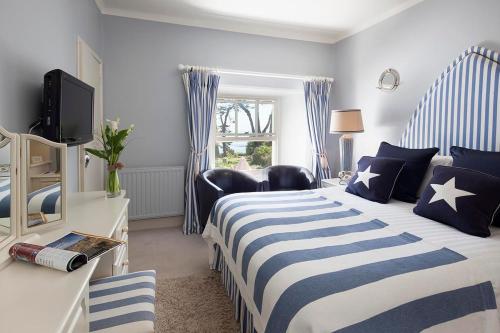 a blue and white bedroom with a bed and a television at Talland Bay Hotel, Looe in Talland