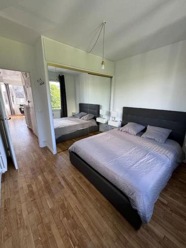 une chambre avec deux lits et un grand miroir dans l'établissement Charmant appartement t3 avec balcon, centre-ville, à Lorient
