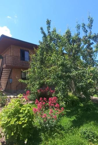 a garden with pink flowers in front of a building at У Эльмиры in Kaji-Say