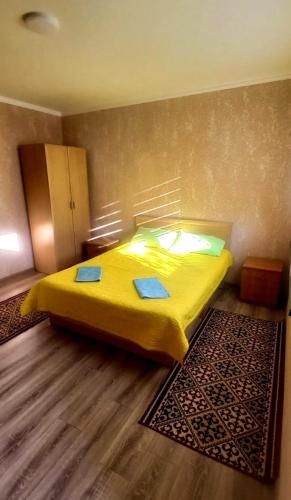 a bedroom with a yellow bed and a rug at У Эльмиры in Kaji-Say