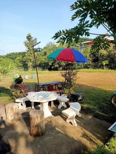 a picnic table with a colorful umbrella and chairs at บ้านสวนสบายใจโฮมสเตย์ ใกล้มหาวิทยาลัยแม่ฟ้าหลวง in Ban Tham Pha Tong