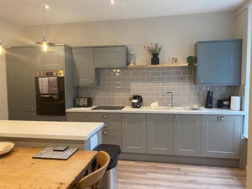 a kitchen with gray cabinets and a wooden table at Ash Cottage in Windermere
