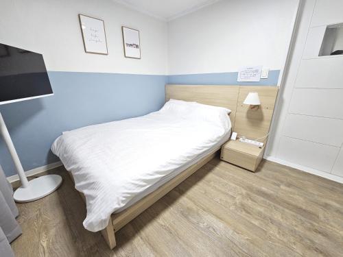 a small bedroom with a bed with white sheets at OMG house in Seoul