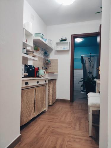 a kitchen with white walls and wooden floors at La casa del glicine Marrubiu in Marrùbiu