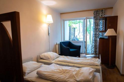 a hotel room with two beds and a chair at Przystań Lubniewice - Pokoje Gościnne in Lubniewice