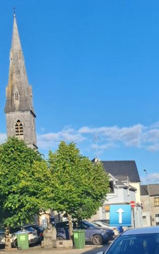 a church with a steeple and a parking lot with cars at Ivy House Apartment in Ennis town with private access in Ennis