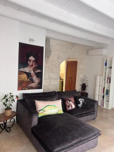una sala de estar con un sofá de cuero negro y una pintura en La Maison Perrin, en Aigues-Mortes