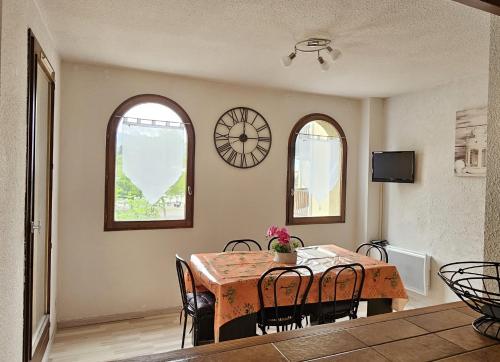une salle à manger avec une table, des chaises et une horloge dans l'établissement APPT T2 saisonnier en montagne, à Jausiers