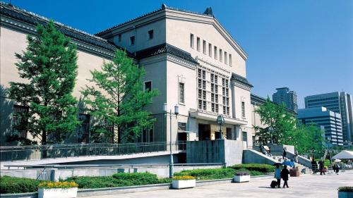 a large building with people walking in front of it at Hotel International House Osaka in Osaka
