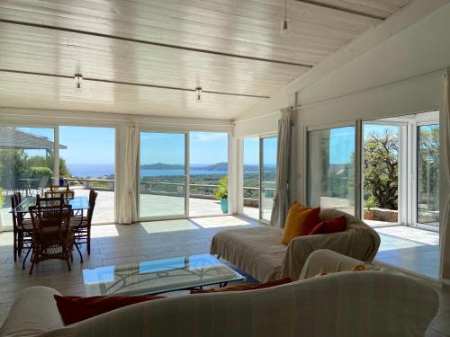 un salon avec un canapé, des chaises et des fenêtres dans l'établissement Villa Alteto magnifique vue mer, piscine, à Zonza
