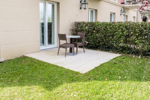 two chairs and a table in a yard at Tulip Inn Honfleur Residence & Spa in Honfleur