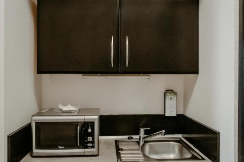 a kitchen with a sink and a microwave at Tulip Inn Honfleur Residence & Spa in Honfleur