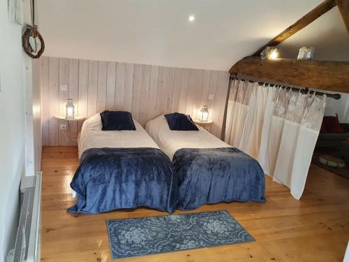 two beds in a room with wooden floors at Gite spacieux - 3 chambres - Calme et charmant in Cubnezais