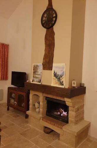 a living room with a fireplace with a clock on the wall at Gite spacieux - 3 chambres - Calme et charmant in Cubnezais