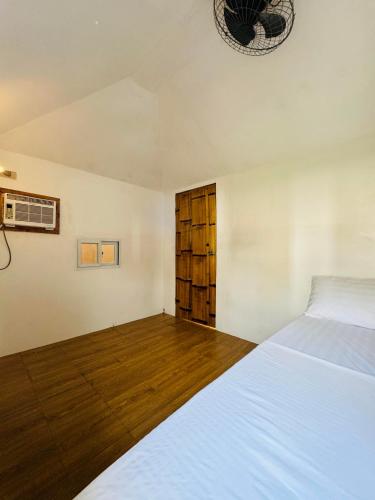 a bedroom with a white bed and wooden floors at Villa Del Cascel in Bulala