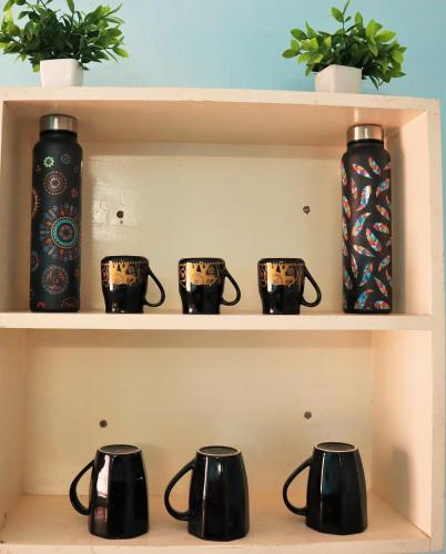 a shelf with four black coffee mugs on it at Good Vibes Home stay in Puttaparthi