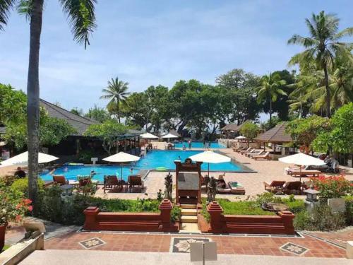 una piscina con sillas y sombrillas en un resort en C&C Jayakarta Apartment Legian Kuta Bali, en Seminyak