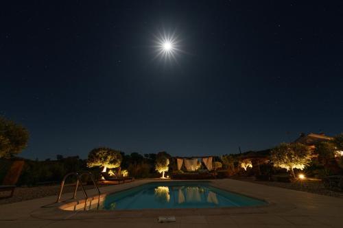 a swimming pool at night with the moon at Corvatos Casas do Monte in Almodôvar