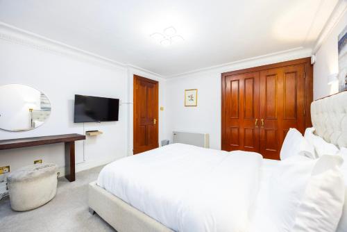 a white bedroom with a large bed and a tv at CARLTON COURT - MAYFAIR in London