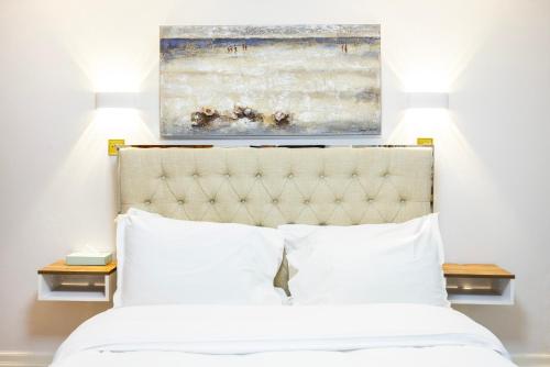 a bed with white pillows and a painting above it at CARLTON COURT - MAYFAIR in London