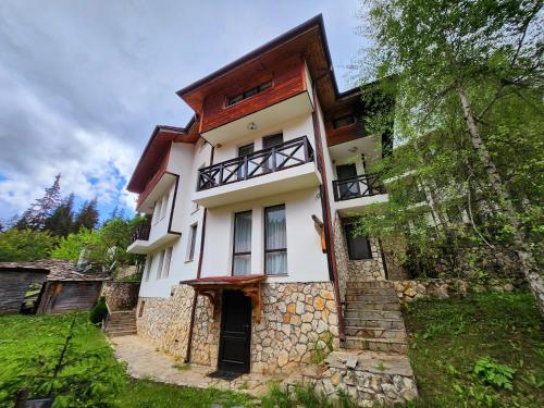 a large white house with a stone wall at Borche Family Homes in Pamporovo