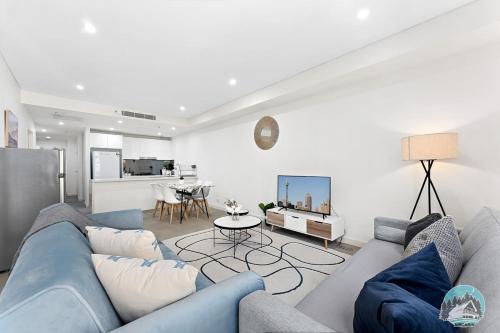 a living room with a blue couch and a kitchen at Aircabin - Mascot - Comfy - Family-2 Beds Apt in Sydney