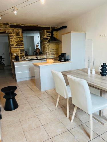 - une cuisine avec une table en bois et des chaises blanches dans l'établissement La Maison Cosy, à Frontenay