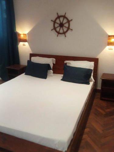a bedroom with a large white bed with a wooden headboard at Villa en résidence proche de l'aéroport in Ambohibao