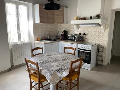 una cucina con tavolo e sedie e una cucina con piano cottura di Chez la Mamé ad Alès