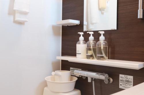 a bathroom with a toilet with bottles on a shelf at Mova Villa Okino in Kikuyo