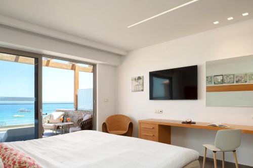 a bedroom with a bed and a desk and a television at High Beach Resort in Malia