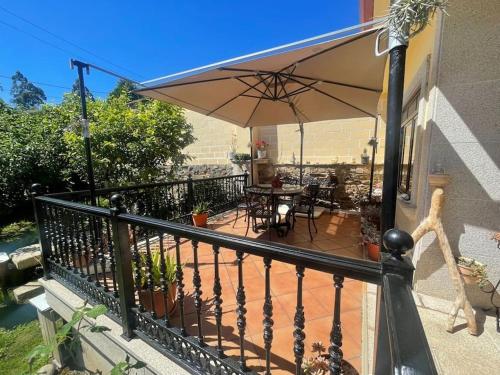 a balcony with an umbrella and a table and chairs at Casa en Costa da Morte,Casa Añón in Neaño