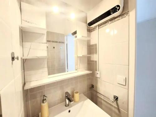 Un baño blanco con lavabo y espejo. en Le TIKAL studio 4 pers, centre-ville port, clim, en La Grande-Motte