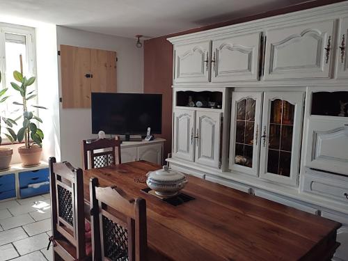 un salon avec une table en bois et des armoires blanches dans l'établissement Maison de bourg spacieuse avec terrasse, à Palluau