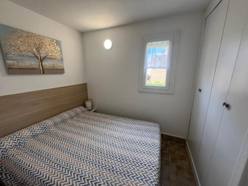une petite chambre avec un lit et une fenêtre dans l'établissement SABLES D'OR Joli T3 proche de la mer Plage Richelieu Cap d'Agde, au Cap d'Agde