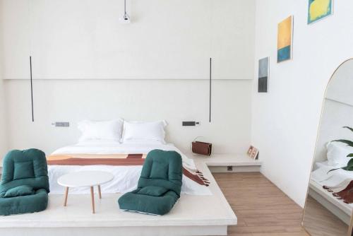 a bedroom with a bed and two green chairs at 夕下青野民宿 The Setting Sun in Qiantan